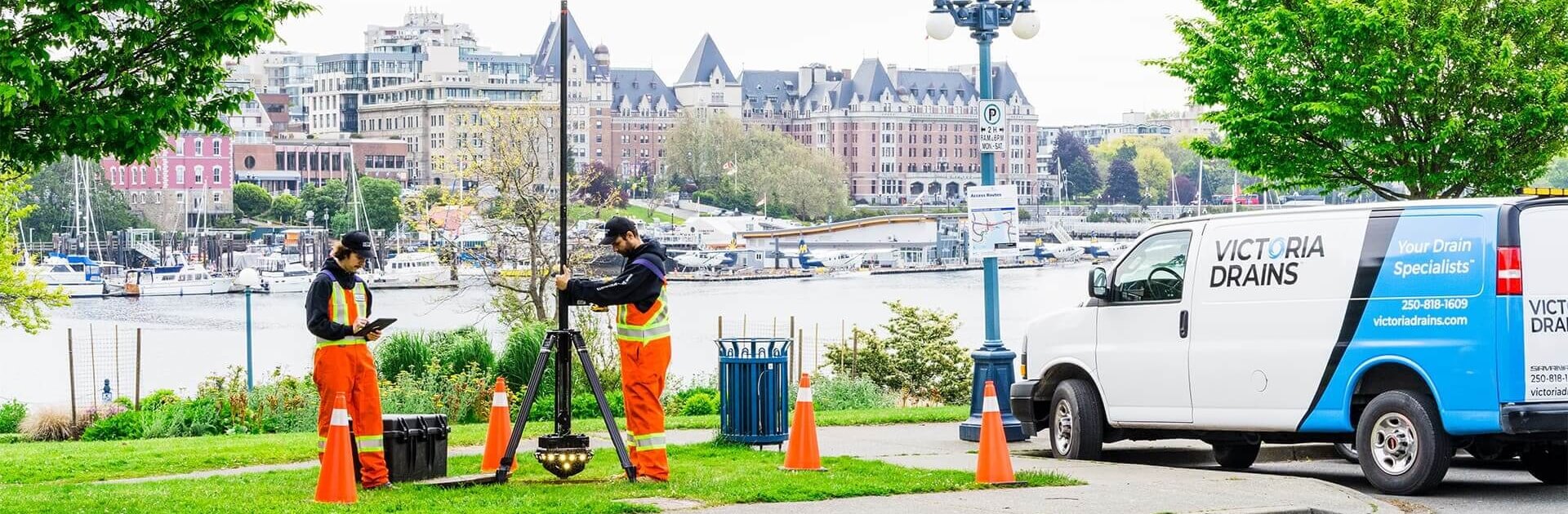 Two main in orange saftey gear using a manhole mapping device